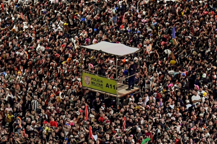 Des officiers de la police militaire se tiennent sur une plateforme surélevée alors que des fans attendent le début du méga-concert gratuit de la pop star américaine Lady Gaga sur la plage de Copacabana à Rio de Janeiro, au Brésil, le 3 mai 2025 ( AFP / Daniel RAMALHO )