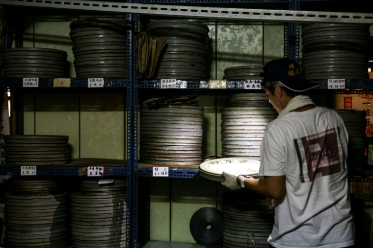 Un employé de l'Institut taïwanais du cinéma et de l'audiovisuel (TFAI) sélectionne la bobine d'un vieux film taïwanais à restaurer, le 29 mai 2026 à Changhua, dans la province de Taïwan ( AFP / I-Hwa Cheng )