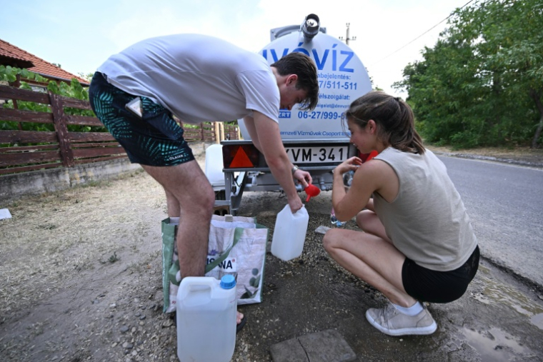 Des habitants viennent remplir des bidons d'eau  à Szada, en Hongrie, le 30 juin 2026 ( AFP / Attila KISBENEDEK )
