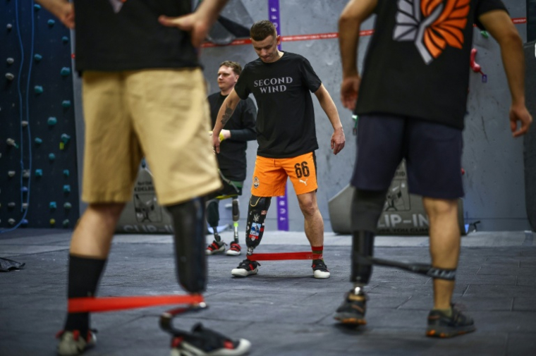 Des anciens soldats ukrainiens blessés au combat et portant des prothèses de jambe, avant une séance d'escalade à Kiev, le 26 février 2026  ( AFP / HENRY NICHOLLS )