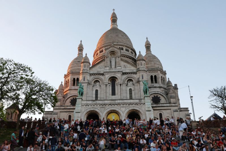 Des touristes assis sur les escaliers devant la basilique du Sacré-Cœur à Montmartre
