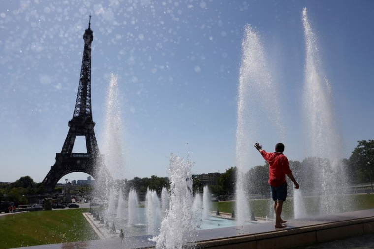 Un touriste se rafraîchit dans la fontaine du Trocadéro à côté de la Tour Eiffel alors qu'une vague de chaleur précoce frappe Paris