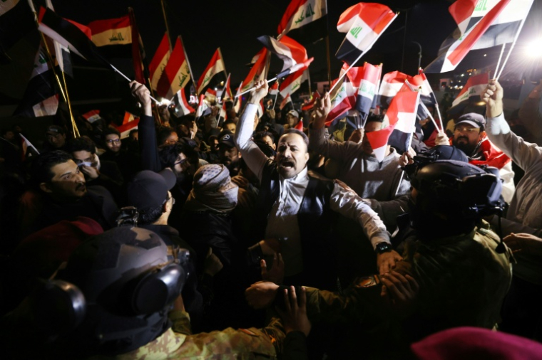 Des Irakiens brandissent des drapeaux lors d'une manifestation à l'entrée du pont suspendu, l'une des entrées de la Zone verte à Bagdad, le 28 janvier 2026 ( AFP / AHMAD AL-RUBAYE )