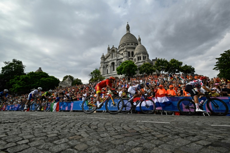 Le peloton passe devant la basilique du Sacré-Coeur à Montmartre lors de la course en ligne hommes des Jeux olympiques de Paris, le 3 août 2024 ( AFP / JULIEN DE ROSA )