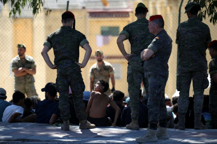 Un jeune migrant regarde un militaire espagnol, avant d'être escorté avec d'autres migrants vers le Maroc, le 2 août 2026 dans l'enclave espagnole de Ceuta ( AFP / Henry NICHOLLS )