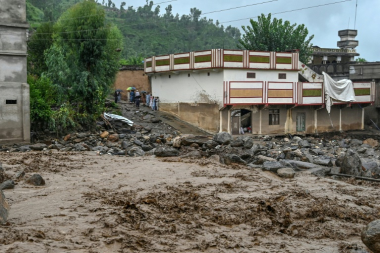 Des villageois (c) près d'un bâtiment alors que le niveau des eaux de crue monte dans le district de Buner, dans la province de Khyber Pakhtunkhwa, le 18 août 2025 au Pakistan ( AFP / Abdul MAJEED )