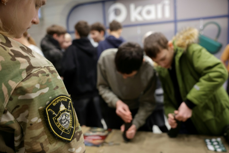 Des participants apprennent à démonter et à remonter une maquette de fusil Kalachnikov lors d'une démonstration au "Club cosaque militaro-sportif Berkut" dans un centre commercial de Voronej, le 24 janvier 2026 en Russie ( AFP / TATYANA MAKEYEVA )