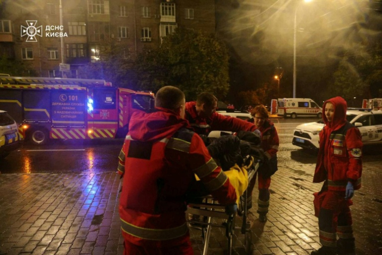 Photo publiée par le Service d'urgence de l'État ukrainien, le 10 octobre 2025, montre des secouristes transportant une personne blessée après des frappes massives de drones et de missiles russes sur Kiev ( Service d'urgence de l'État ukrainien / Handout )