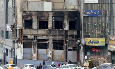 Des passants le 19 janvier 2026 devant un immeuble détruit lors des manifestations à Téhéran, en Iran ( AFP / ATTA KENARE )