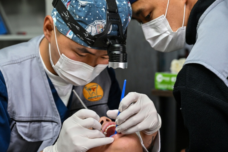 Un dentiste examine la bouche d'un eenfant dans une clinique dentaire mobile à Oulan-Bator, le 28 août 2026  ( AFP / Hector RETAMAL )