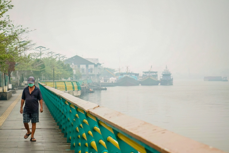 Un homme porte un masque de protection, alors qu'une brume causée par des feux de forêt recouvre le village de Benua Melayu Laut, à Pontianak, dans le Kalimantan occidental, le 17 septembre 2026 en Indonésie ( AFP / DITO )