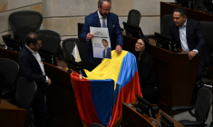 Des membres du Sénat colombien déposent une photo de Miguel Uribe avec la phrase "Nous t'attendons" sur un drapeau colombien au-dessus de son siège au Parlement à Bogota, le 9 juin 2025 ( AFP / Raul ARBOLEDA )