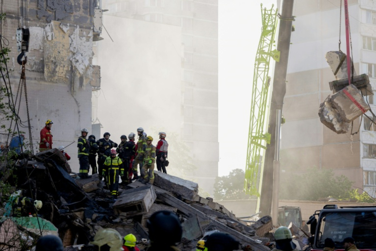 Des secouristes sur le site d'une frappe russe ayant partiellement détruit un immeuble résidentiel à Kiev, le 14 mai 2026  ( AFP / Tetiana DZHAFAROVA )