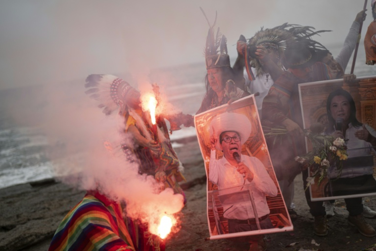 Des chamans tiennent des affiches des candidats à la présidentielle Roberto Sanchez (à gauche) et Keiko Fujimori lors d'un rituel destiné à prédire le vainqueur du second tour de l'élection présidentielle péruvienne, sur la plage de La Herradura à Lima, le 1er juin 2026 ( AFP / ERNESTO BENAVIDES )