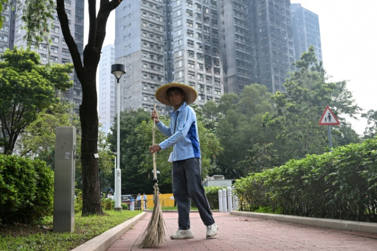 Un balayeur devant les tours sinistrées du complexe résidentiel de complexe résidentiel de Wang Fuk Court à Hong Kong, le 20 avril 2026 ( AFP / Peter PARKS )