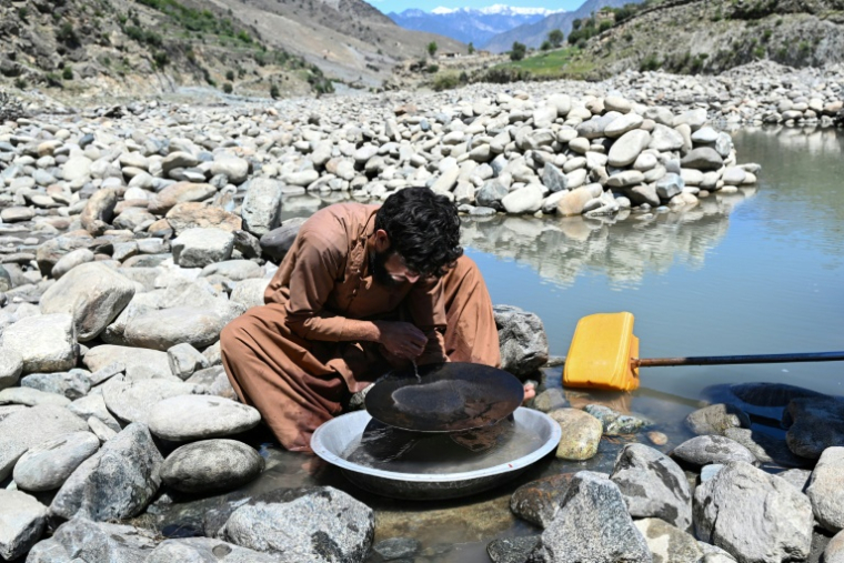 Un homme cherche de l'or en utilisant la technique traditionnelle de l'orpaillage, après avoir trié les pépites extraites des pierres de la montagne, provenant du lit de la rivière Kunar, dans le district de Naray de la province de Kunar, le 13 avril 2026 en Afghanistan ( AFP / Wakil KOHSAR )