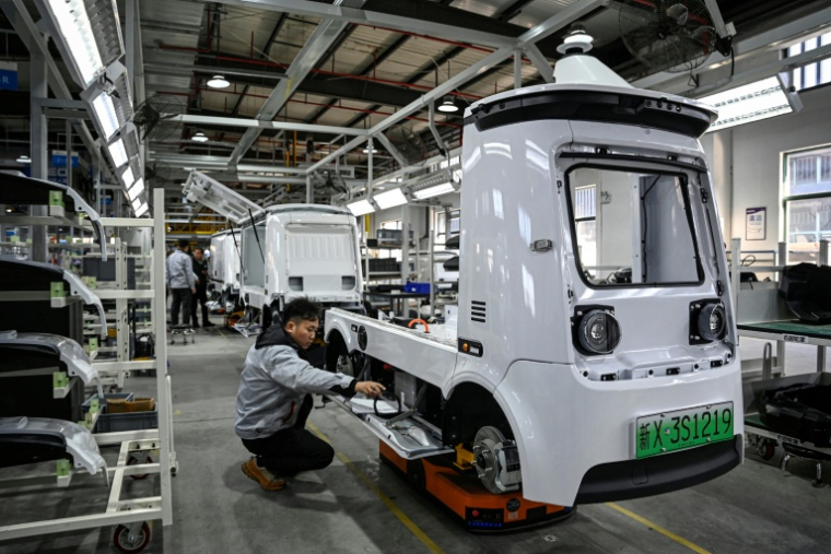 Des ouvriers travaillent sur une ligne de production de l'usine Neolix qui fabrique de petits véhicules utilitaires autonomes pour le transport de colis en ville, le 4 décembre 2025 à Yancheng dans la province chinoise du Jiangsu  ( AFP / Jade GAO )