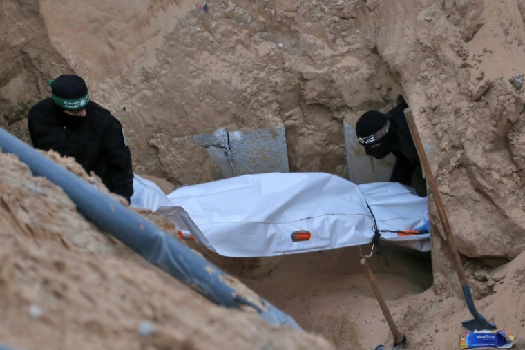 Des combattants cagoulés du Hamas transportent un corps retrouvé dans un tunnel au nord de Khan Younès, dans le sud de la bande de Gaza, le 28 octobre 2025  ( AFP / Bashar TALEB )