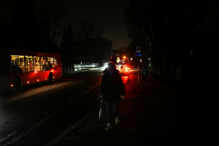 Une femme marche dans une rue non éclairée lors d'une panne de courant à Lviv, le 3 décembre 2025,en Ukraine ( AFP / Sergei GAPON )