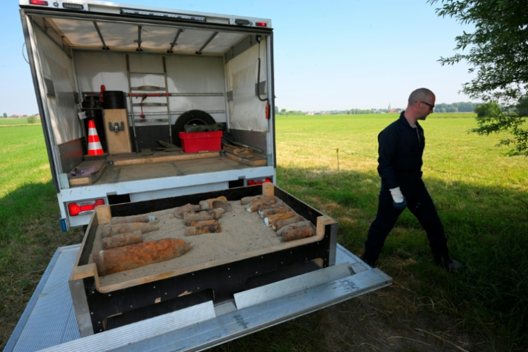 Des membres de l'équipe de déminage de la DOVO collectent de vieux obus de la Première Guerre mondiale trouvés dans la campagne du nord-ouest de la Belgique, près d'Ypres, le 19 mai 2025 ( AFP / Nicolas TUCAT )