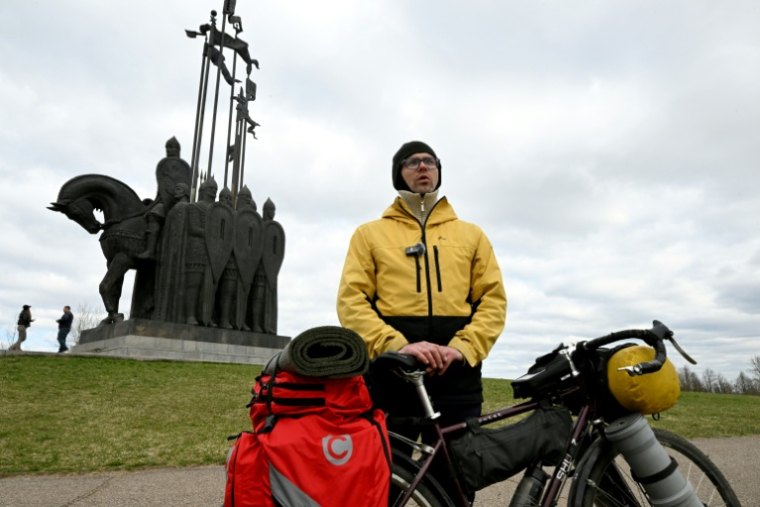 Dmitri Joukov, un aventurier-voyageur russe de 37 ans, répond aux questions de l'AFP devant le monument dédié au héros médiéval russe Alexandre Nevski sur la berge du Lac Peïpous dans la région de Pskov le 20 avril 2026 ( AFP / Olga MALTSEVA )