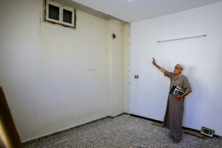 Mustafa Khaled Alwan montre l'emplacement du faux mur qui dissimulait sa bibliothèque, chez lui à Homs, en Syrie, le 19 septembre 2026 ( AFP / Bakr ALKASEM )