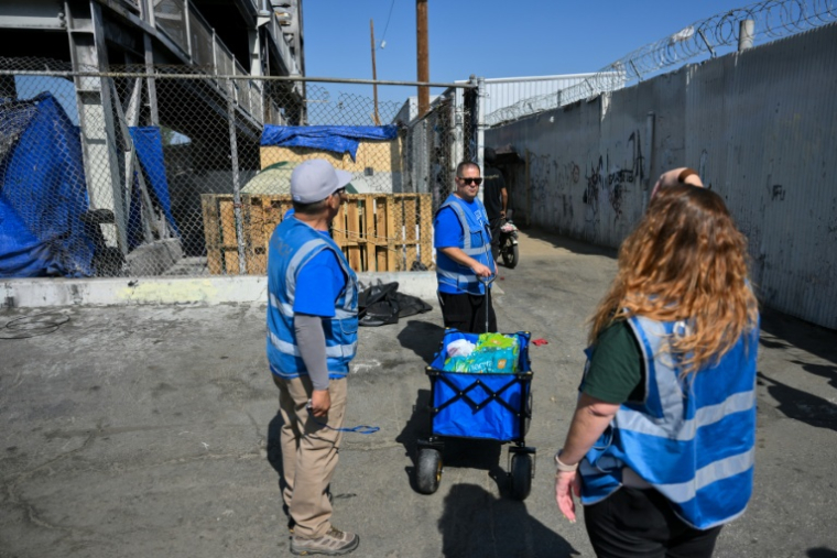 Armando Covarrubias (au centre) et ses collègues de l'association Hope The Mission distribuent de l'eau et de la nourriture dans un campement de sans-abris à Los Angeles, le 1er juin 2026 ( AFP / Patrick T. Fallon )