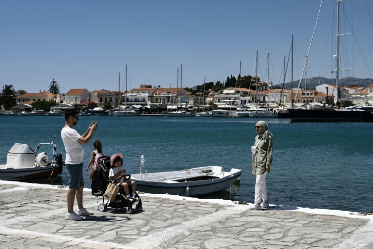 Une famille venue de Turquie prend des photos dans le village de Pythagorion, sur l’île de Samos, le 24 juillet 2026 ( AFP / Sakis Mitrolidis )