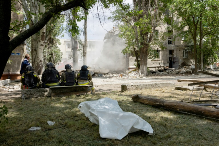 Des secouristes sont assis devant un corps sans vie avec un bâtiment effondré en arrière-plan après une frappe russe à Kramatorsk le 22 juin 2025 ( AFP / Tetiana DZHAFAROVA )