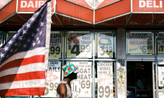 Une personne passe devant une épicerie et un drapeau américain dans le quartier de Flatbush, surnommé "Little Haiti", dans l'arrondissement de Brooklyn à New York, aux Etats-Unis, le 15 juillet 2025 ( AFP / CHARLY TRIBALLEAU )