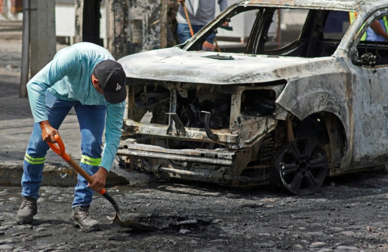 Un homme nettoie la chaussée devant un véhicule calciné à Puerto Vallerta, dans l'Etat de Jalisco, le 23 février 2026 au Mexique ( AFP / ARTURO MONTERO )