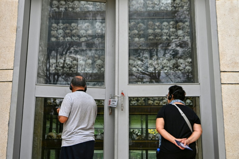 Des touristes regardent les crânes de victimes du génocide des Khmers rouges exposés à Choueng Ek, à Phnom Penh, le 17 avril 2025 ( AFP / TANG CHHIN SOTHY )