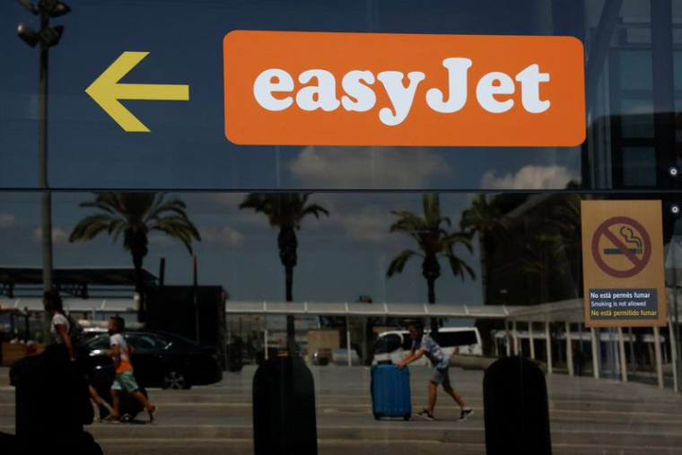 Des passagers se reflétant sur un verre portant le logo Easyjet à l'aéroport Josep Tarradellas de Barcelone-El Prat, à Barcelone