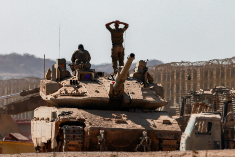 Un soldat israélien se tient sur un char près d'un autre soldat, côté israélien de la frontière avec la bande de Gaza, le 2 septembre 2025 ( AFP / Menahem KAHANA )