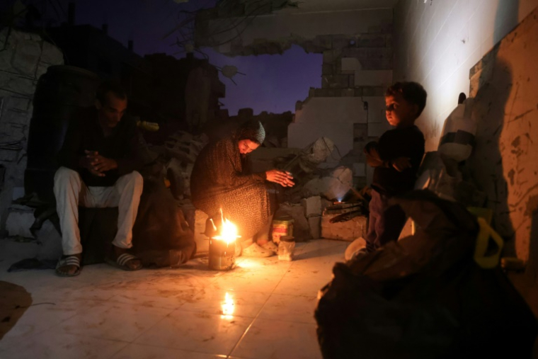 Des Palestiniens allument un feu dans un bâtiment endommagé à Khan Younès où ils ont trouvé refuge,  dans le sud de la bande de Gaza, le 25 octobre 2025 ( AFP / Bashar TALEB )