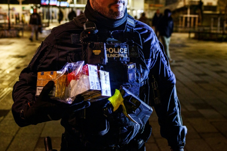 Un policier municipal avec des cartouches de cigarettes de contrebande saisies à Saint-Denis, en Seine-Saint-Denis, le 22 janvier 2026 ( AFP / Dimitar DILKOFF )