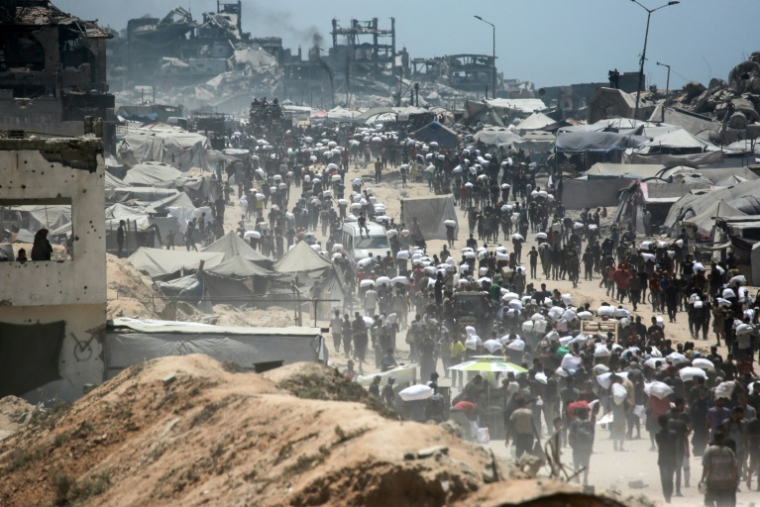 Des Palestiniens portent des sacs de farine à Jabalia, dans le nord de la bande de Gaza, le 1er août 2025 ( AFP / Bashar TALEB )