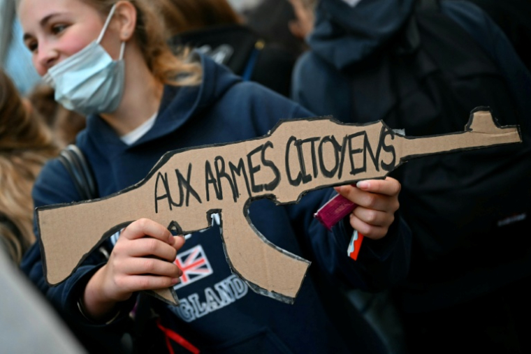 Une élève tient une pancarte en forme de fusil "Aux armes, citoyens" devant le lycée Turgot le 5 octobre 2026 à Paris ( AFP / LOU BENOIST )
