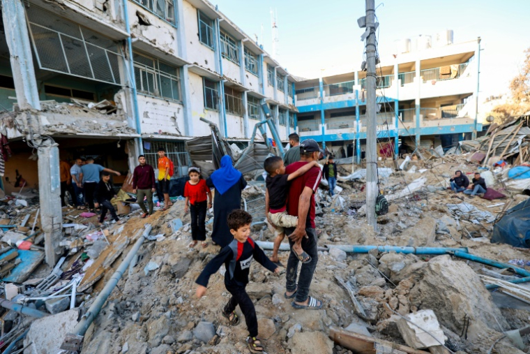 Des Palestiniens au milieu des destructions après une frappe sur une école abritant des déplacés palestiniens à Bureij, dans le centre de la bande de Gaza, le 7 mai 2025 ( AFP / Eyad BABA )