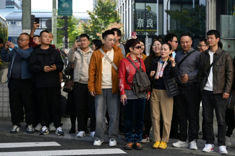Un groupe de touristes chinois attend pour traverser une rue dans le quartier commerçant de Ginza, à Tokyo, le 16 novembre 2025 ( AFP / GREG BAKER )