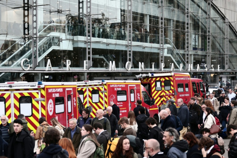 Des pompiers et passagers devant la Gare Montparnasse, partiellement évacuée après le tir d'un policier contre un hommme armé d'un couteau le 14 novembre 2025 à Paris ( AFP / Thibaud MORITZ )
