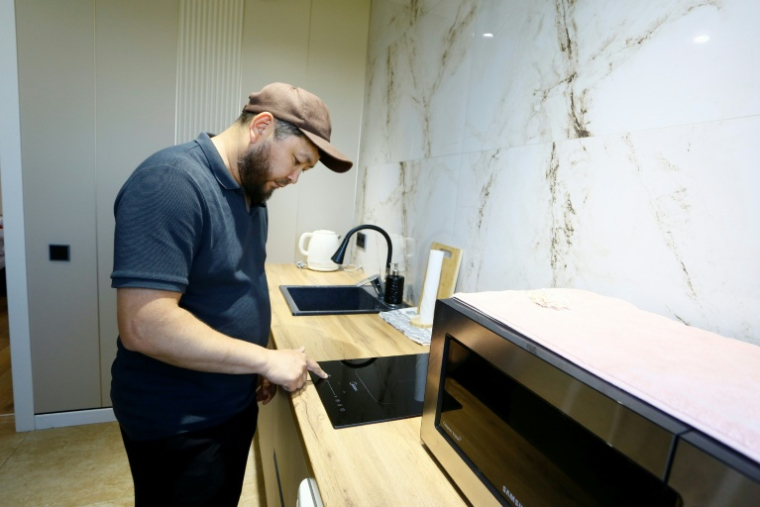 Erik Bekentaïev allume sa plaque à induction  dans son appartement à Chtchoutchinsk, le 27 mai 2026 au Kazakhstan ( AFP / Ruslan PRYANIKOV )