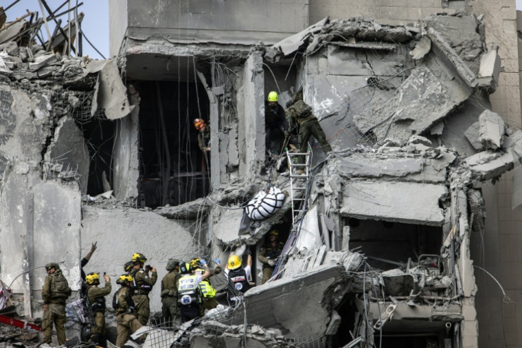 Des membres des secours israéliens évacuent un corps des décombres d'un bâtiment touché par un missile iranien à Beer Sheba, dans le sud d'Israël, le 24 juin 2025 ( AFP / John Wessels )