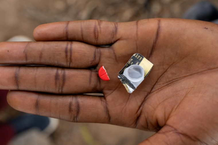Un toxicomane tient la moitié d'un comprimé rouge à base de tapentadol à Abuja, le 24 février 2026 au Nigeria ( AFP / Light Oriye Tamunotonye )