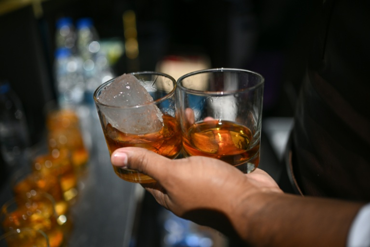 Un barman tient des verres de rhum lors d'un événement organisé par le producteur de rhum Hacienda Santa Teresa, le 13 décembre 2025 à Caracas, au Venezuela ( AFP / Federico PARRA )