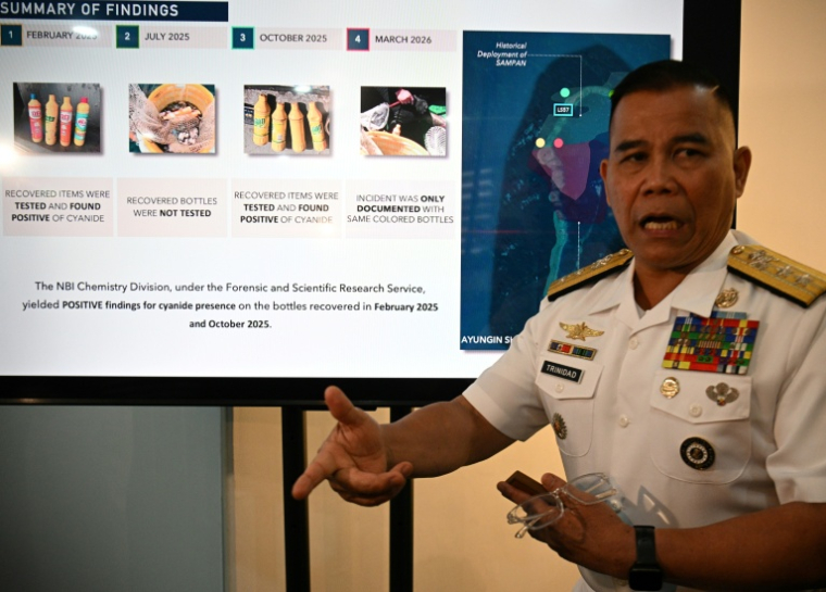 Le porte-parole de la marine philippine Roy Vincent Trinidad, montre des diapositives de bouteilles jaunes saisies, soupçonnées de contenir du cyanure, dans les eaux du banc Second Thomas, en mer de Chine méridionale, lors d'une conférence de presse à Manille, le 13 avril 2026 ( AFP / Ted ALJIBE )
