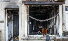 L'entrée et la fenêtre d'une maison brûlées après une deuxième nuit d'émeutes visant des immigrés à Ballymena, le 11 juin 2025 en Irlande du Nord ( AFP / PAUL FAITH )