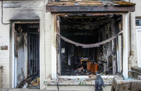 L'entrée et la fenêtre d'une maison brûlées après une deuxième nuit d'émeutes visant des immigrés à Ballymena, le 11 juin 2025 en Irlande du Nord ( AFP / PAUL FAITH )