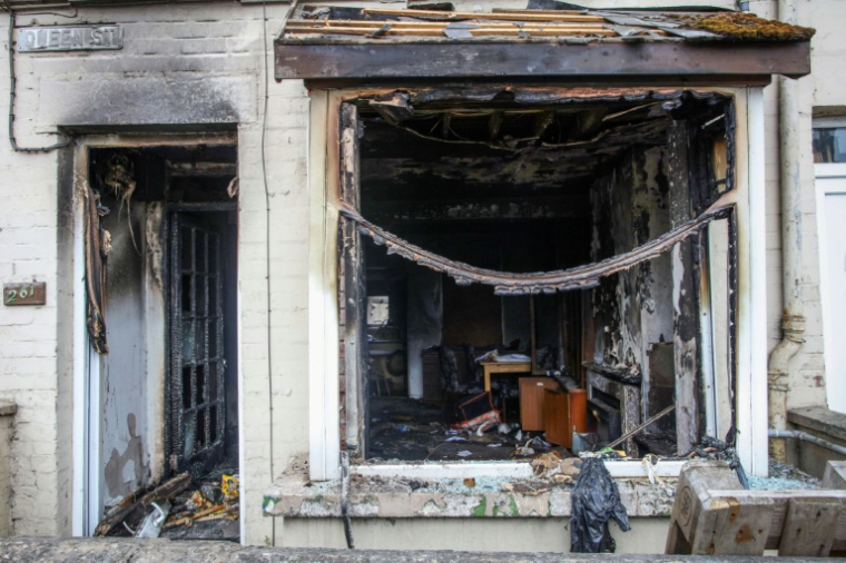 L'entrée et la fenêtre d'une maison brûlées après une deuxième nuit d'émeutes visant des immigrés à Ballymena, le 11 juin 2025 en Irlande du Nord ( AFP / PAUL FAITH )