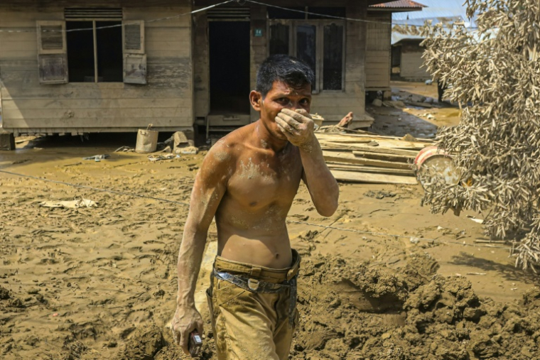 Cette photo prise le 5 décembre 2025 montre un homme couvert de boue devant une maison dans une zone inondée à Aceh Tamiang, dans la province d'Aceh, sur l'île de Sumatra, en Indonésie ( AFP / AMANDA JUFRIAN )
